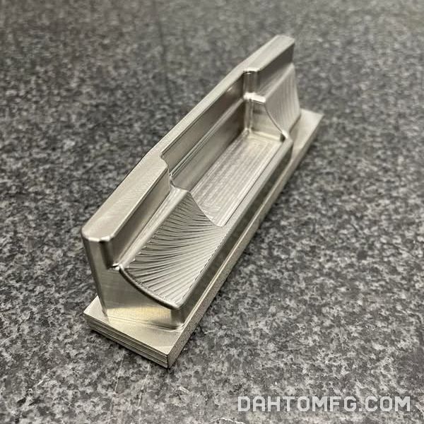 Finished aluminum part with scalloped 3D-surfaced faces, resting on a granite surface plate