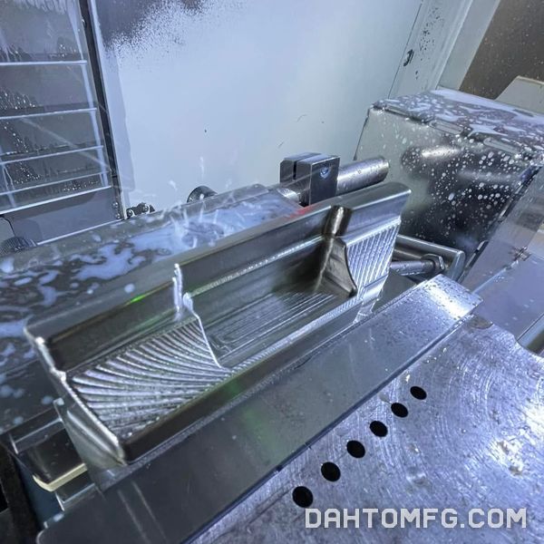 Coolant spraying over a 3D-surfaced aluminum part in the vise