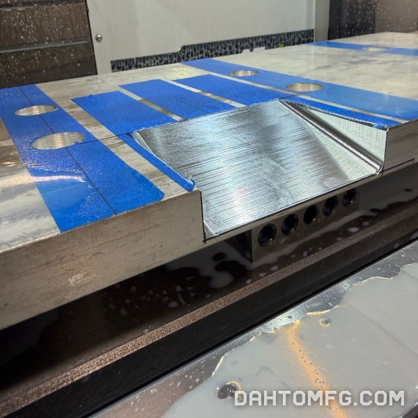Angled face milled into a large aluminum plate, with blue tape on the fixture