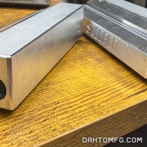 Machined aluminum blocks, one engraved with the word SWEEPER