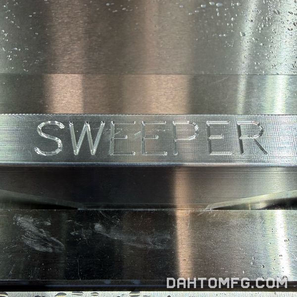 Close-up of engraved SWEEPER lettering on machined aluminum