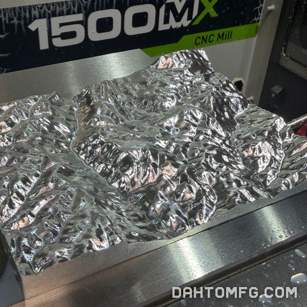 Aluminum block machined into a detailed 3D topographic terrain surface, on the Tormach 1500MX table